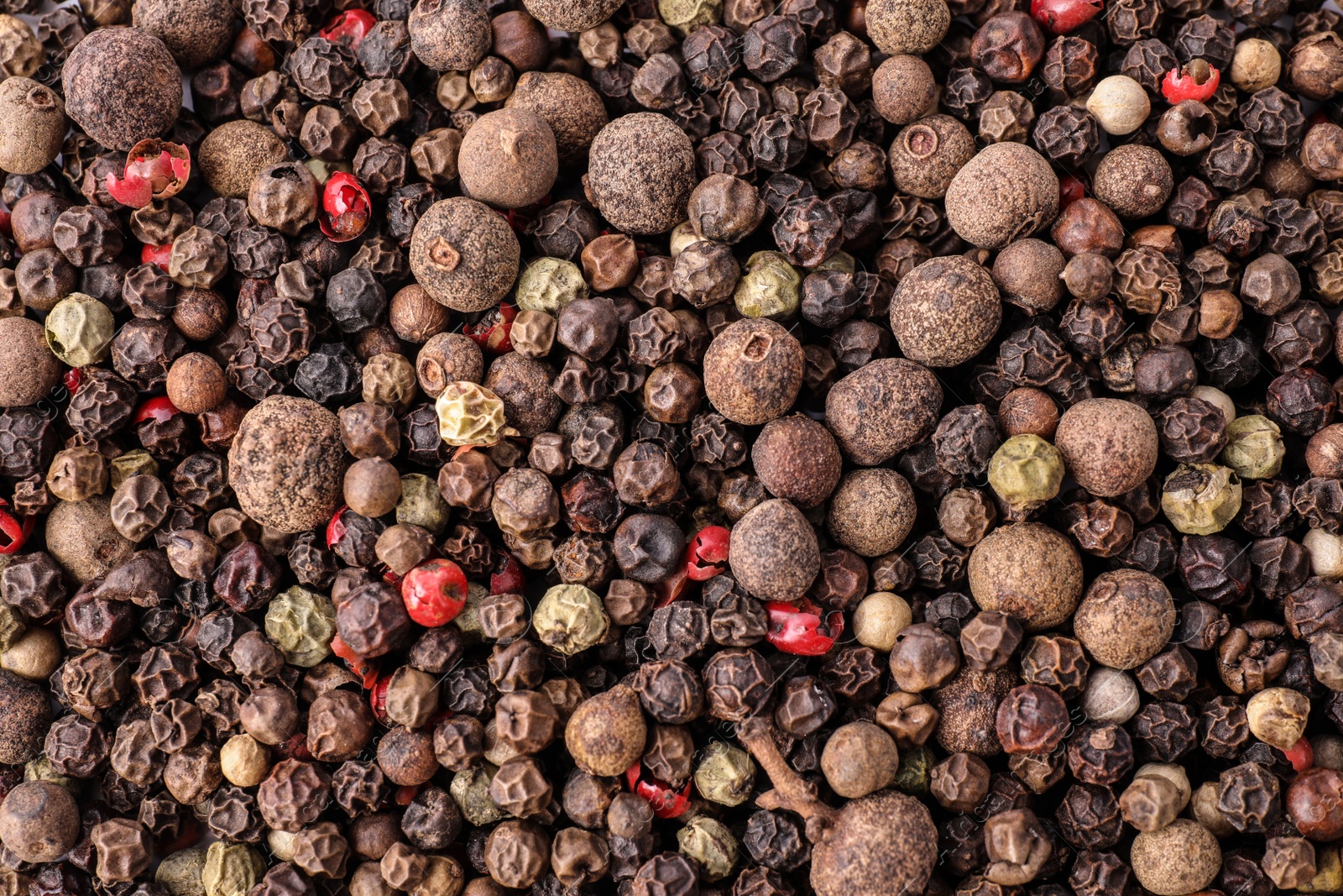 Photo of Pepper grains mix as background, top view