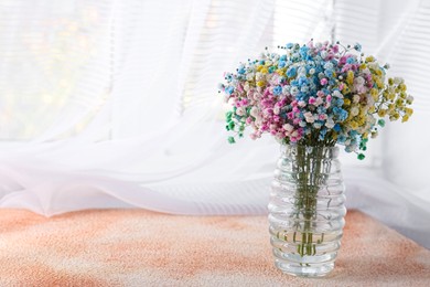 Photo of Beautiful gypsophila flowers in vase on textured table near window. Space for text