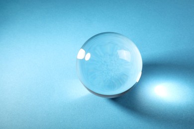 Photo of Transparent glass ball on light blue background