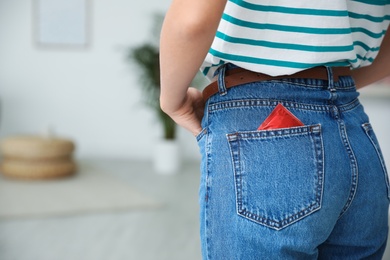 Woman with condom in pocket of her jeans indoors, closeup. Safe sex concept