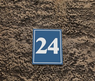 Plate with house number 24 on textured wall outdoors