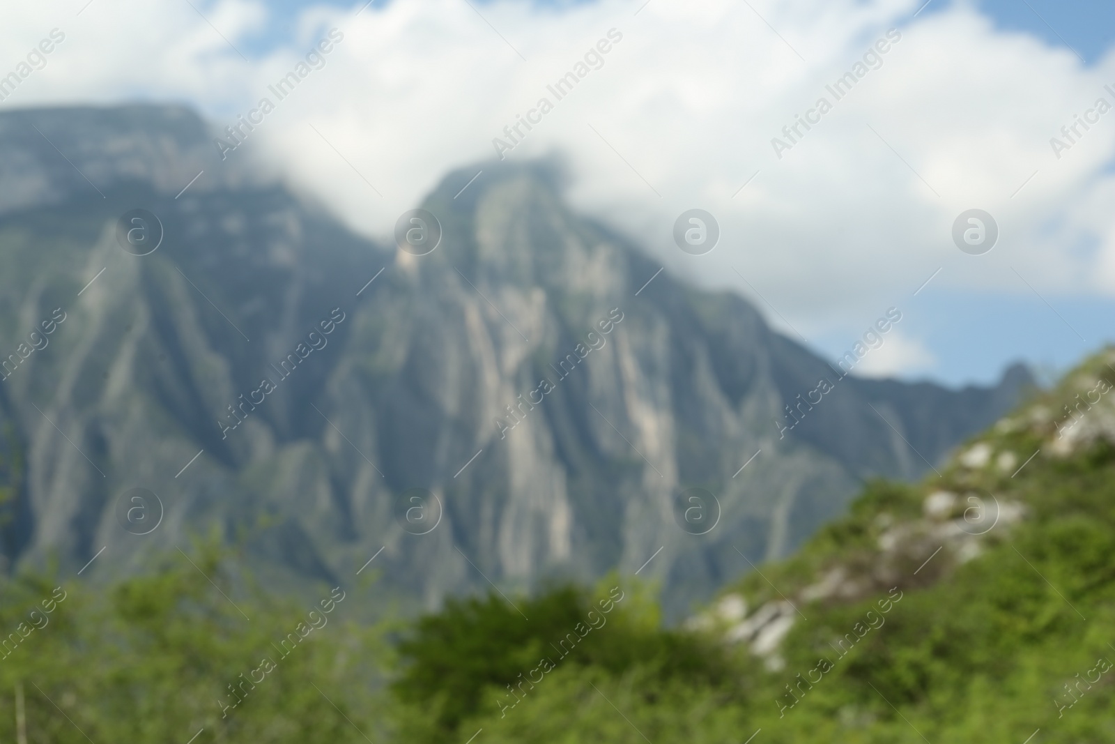 Photo of Beautiful mountains and plants near road under cloudy sky, blurred view