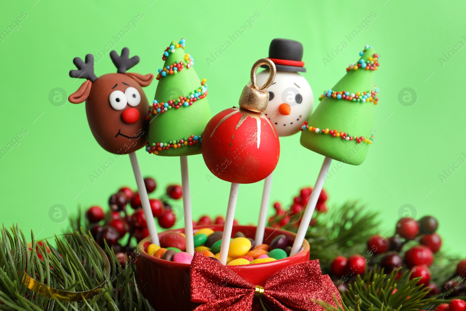 Photo of Delicious Christmas themed cake pops on green background, closeup