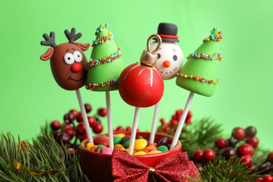 Delicious Christmas themed cake pops on green background, closeup