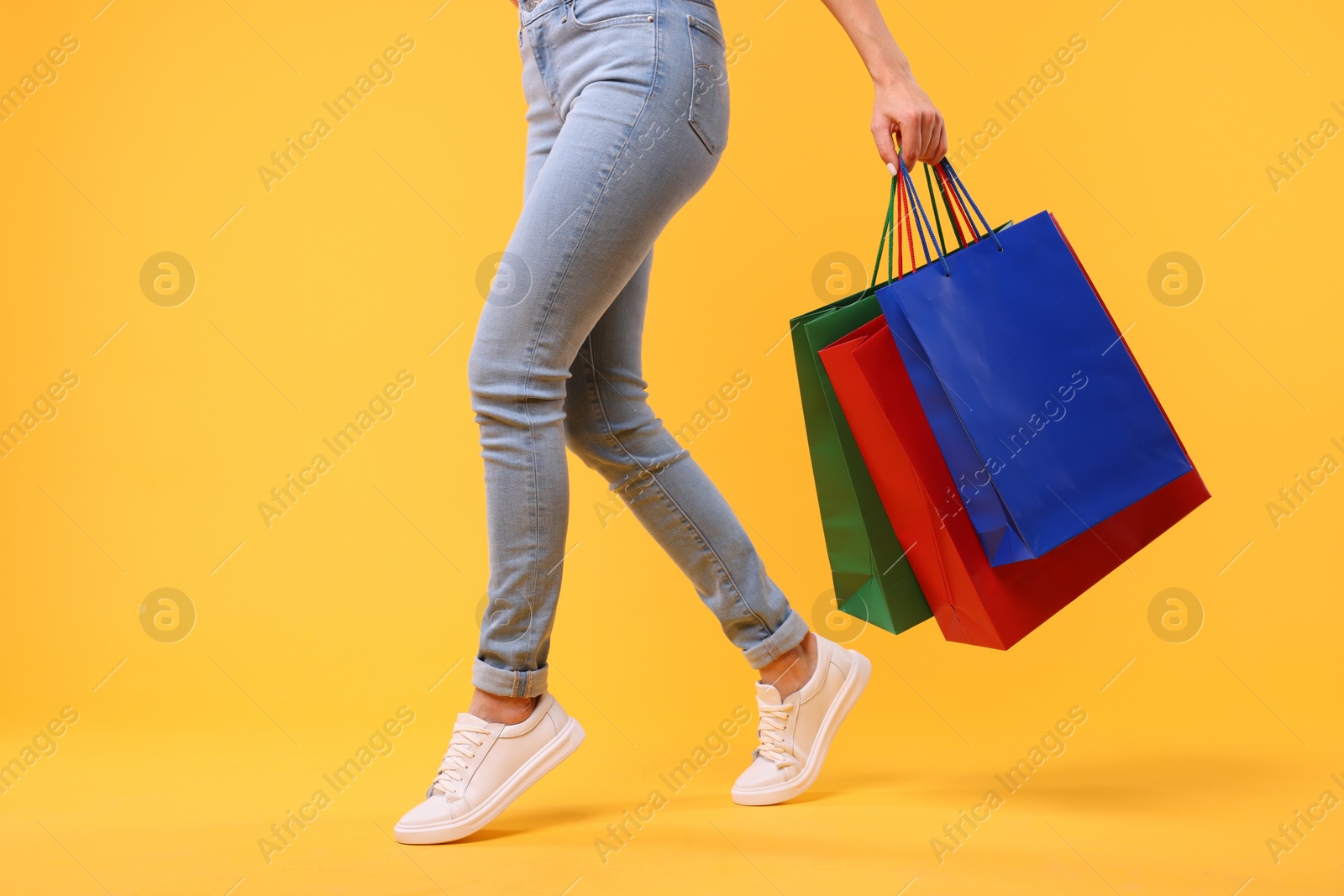 Photo of Woman with shopping bags on yellow background, closeup