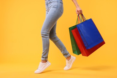 Photo of Woman with shopping bags on yellow background, closeup