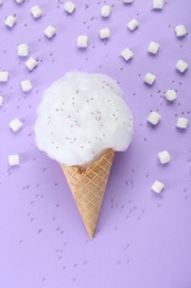 Photo of Sweet cotton candy in waffle cone and marshmallows on purple background, flat lay