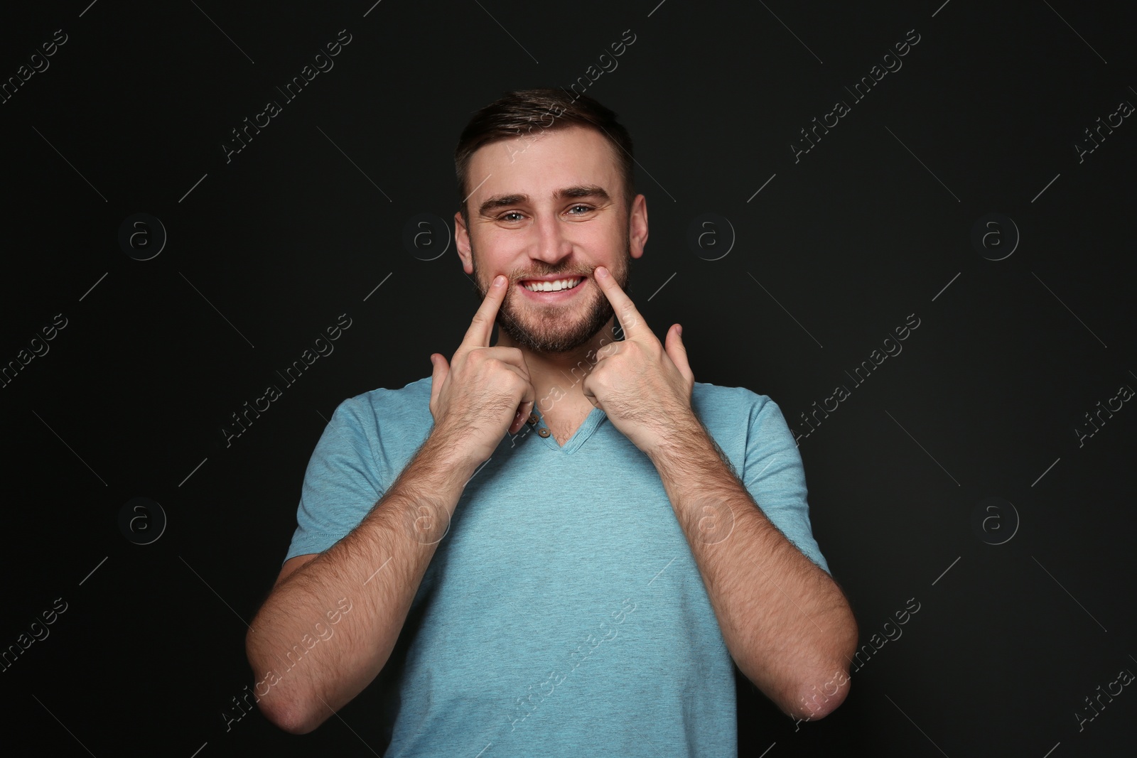 Photo of Man showing LAUGH gesture in sign language on black background