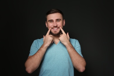 Photo of Man showing LAUGH gesture in sign language on black background