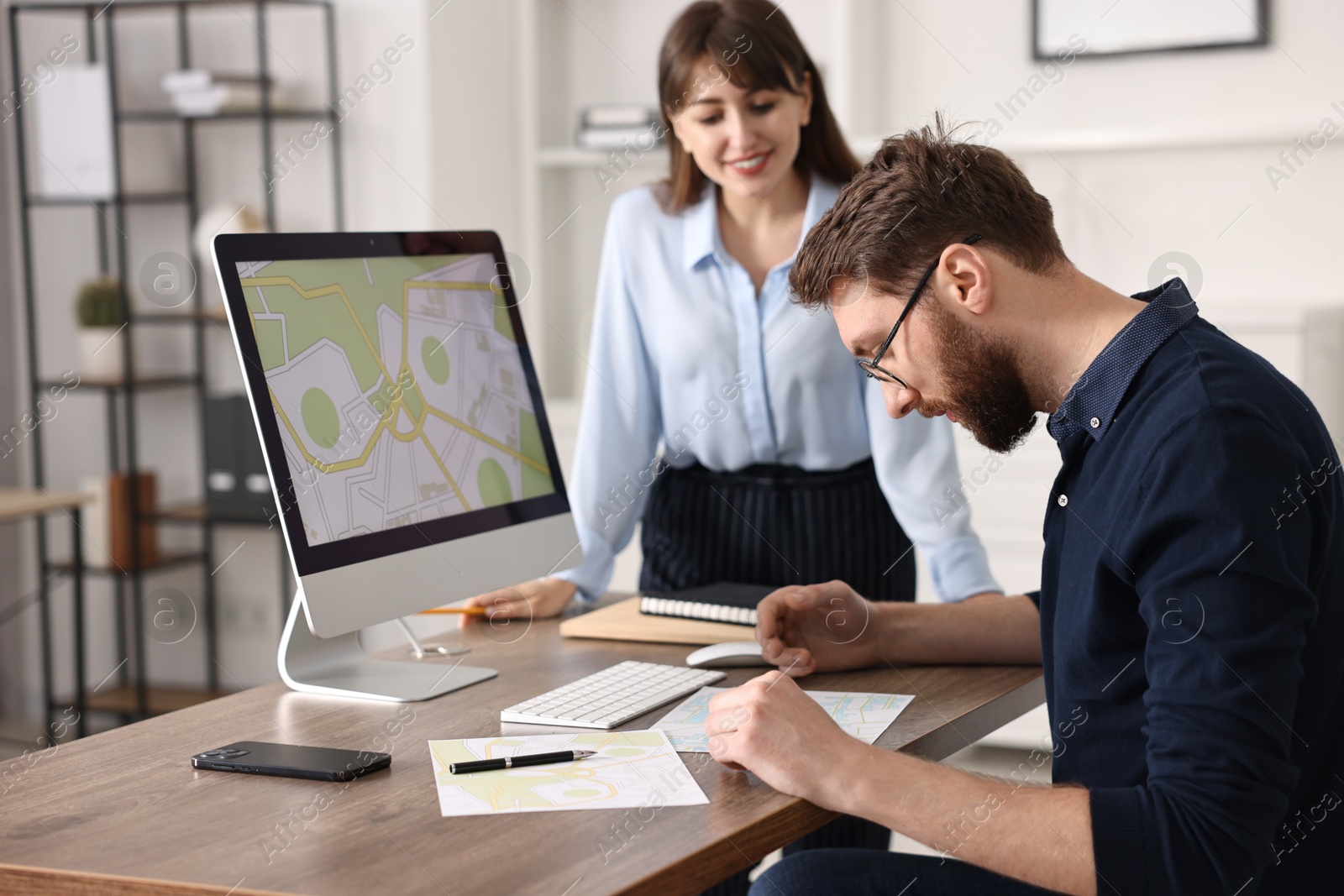 Photo of Cartographers working with cadastral map on computer at table in office