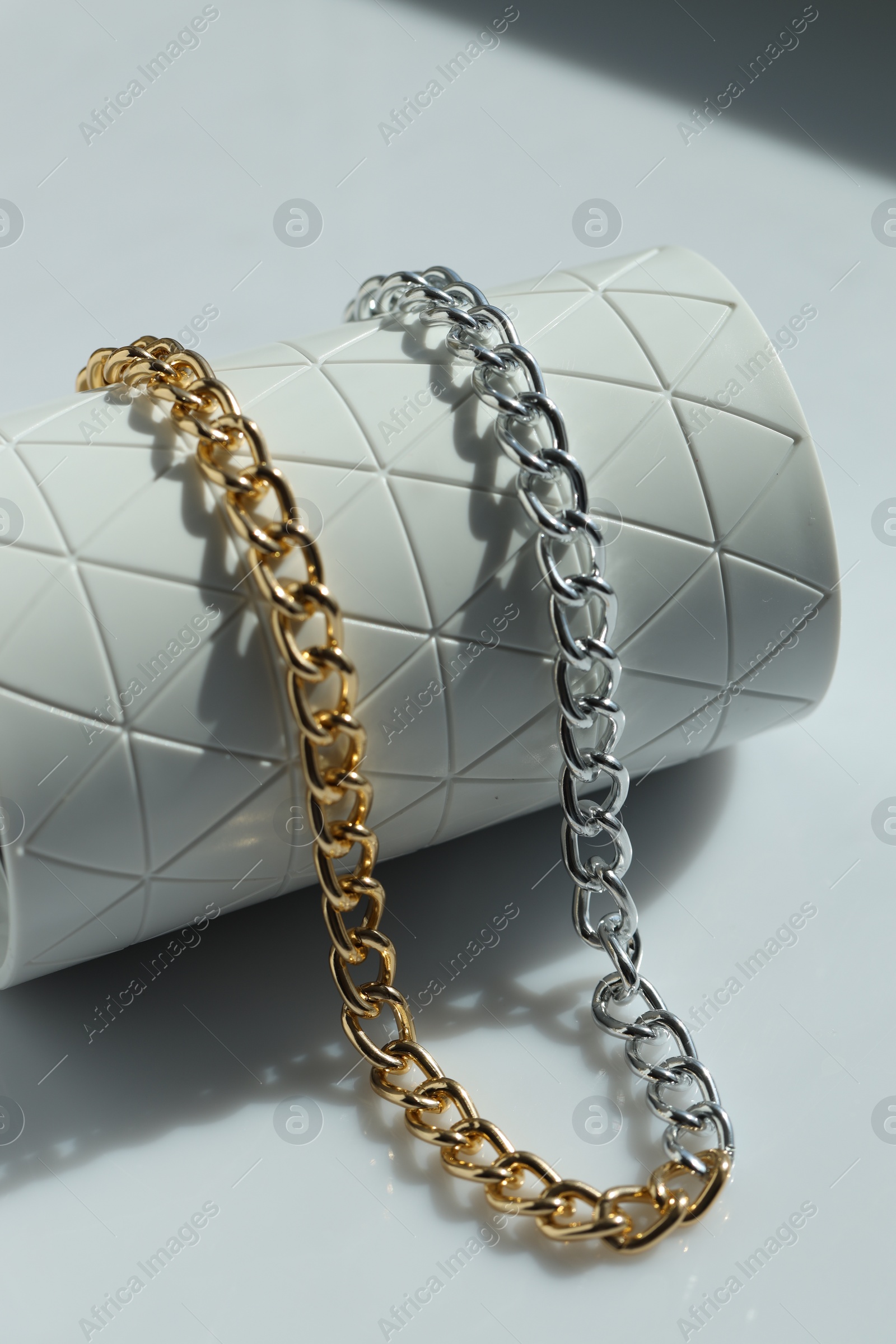 Photo of Metal chain on white table, closeup. Luxury jewelry