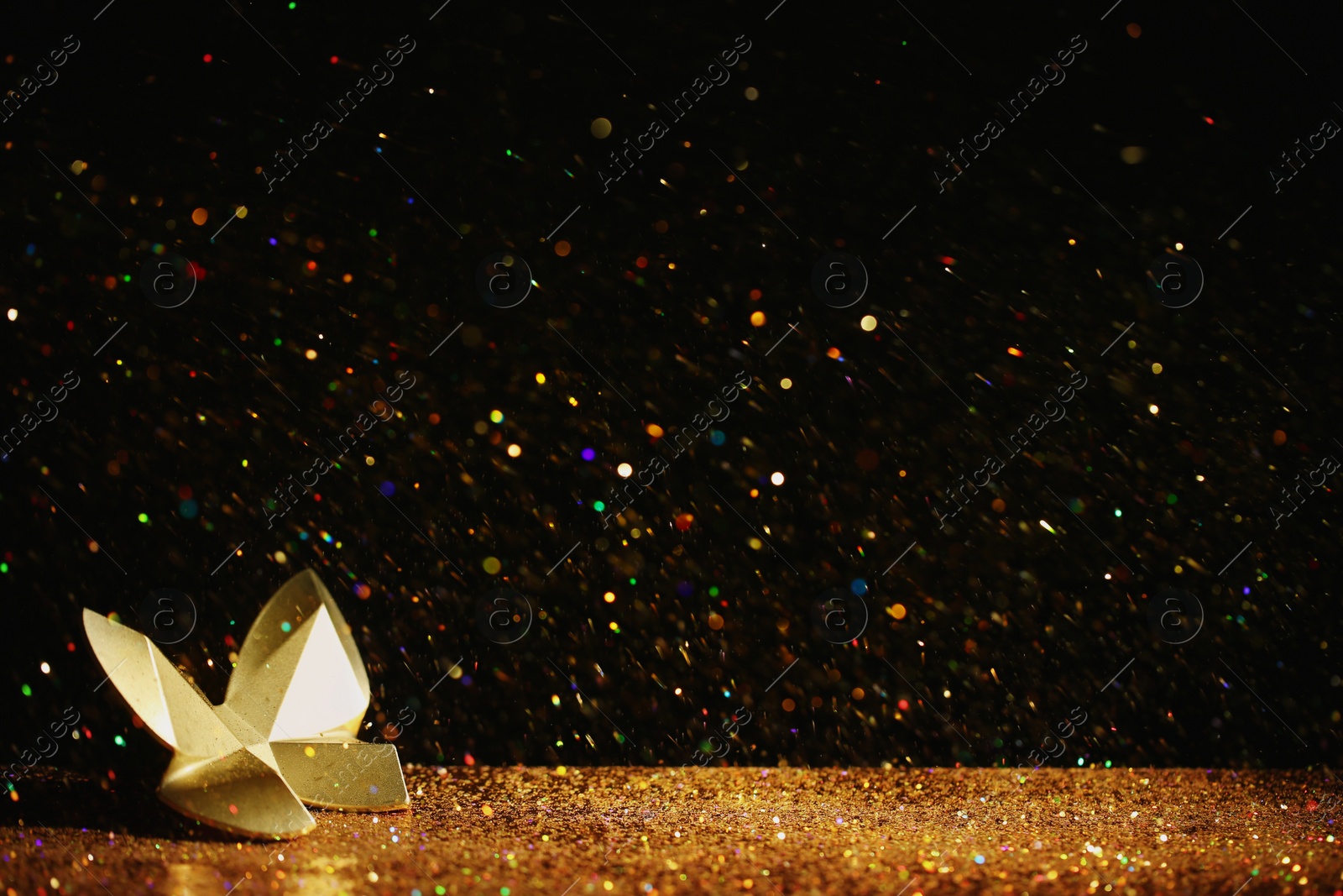 Photo of Golden glitter and decorative butterfly against black background. Space for text