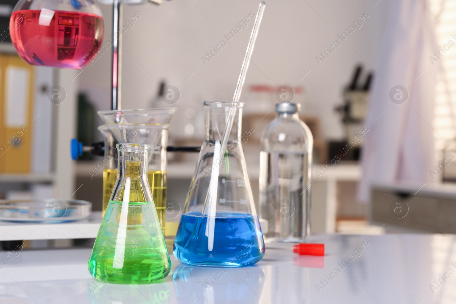 Photo of Laboratory analysis. Glassware with different liquids on white table indoors