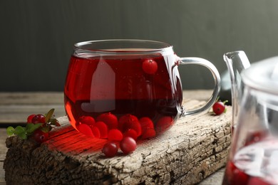 Photo of Delicious cranberry tea and berries on wooden table, closeup