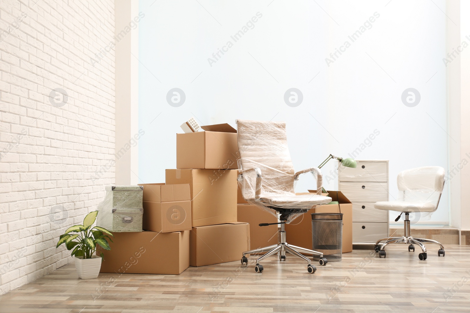 Photo of Moving boxes and stuff near white brick wall in room