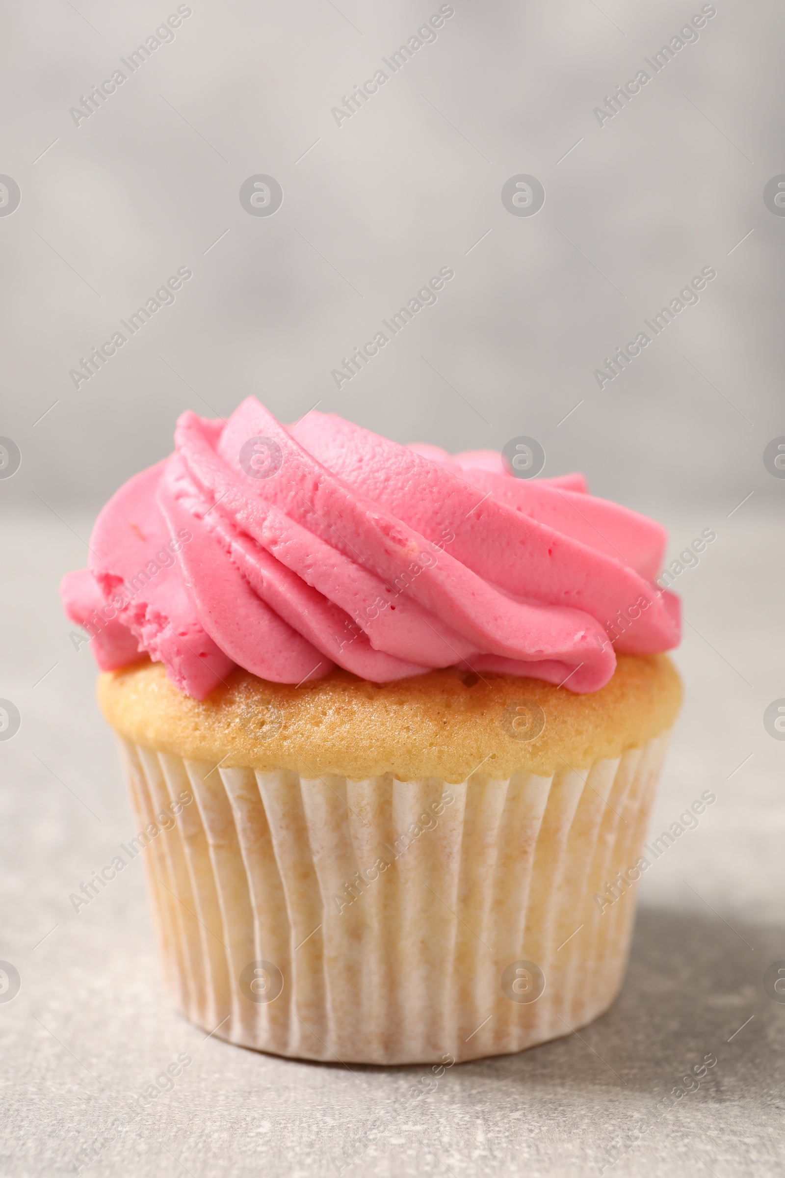 Photo of Delicious cupcake with bright cream on gray table