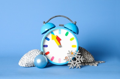 Photo of Alarm clock and Christmas decor on blue background. New Year countdown