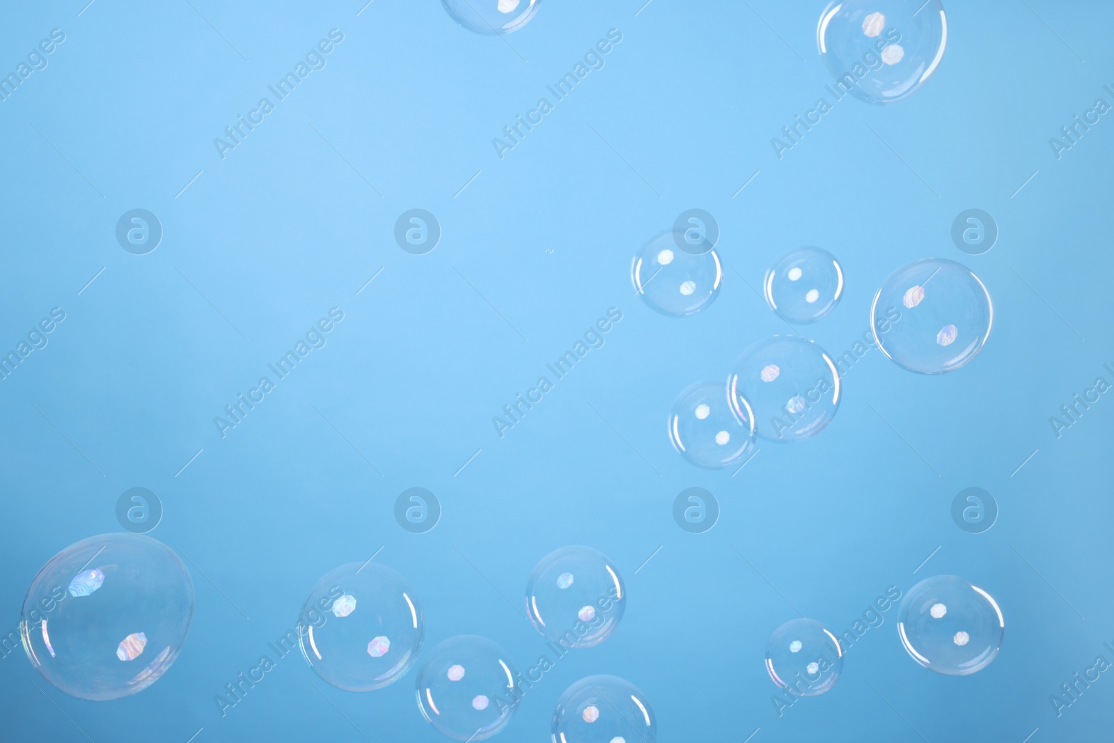 Photo of Many beautiful soap bubbles on light blue background. Space for text