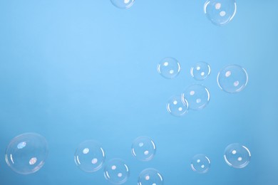 Photo of Many beautiful soap bubbles on light blue background. Space for text