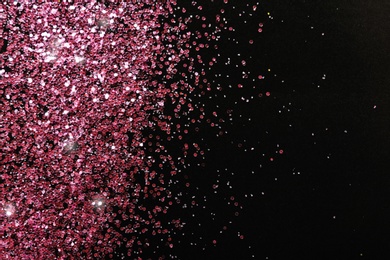 Photo of Rose gold glitter on black background, top view with space for text