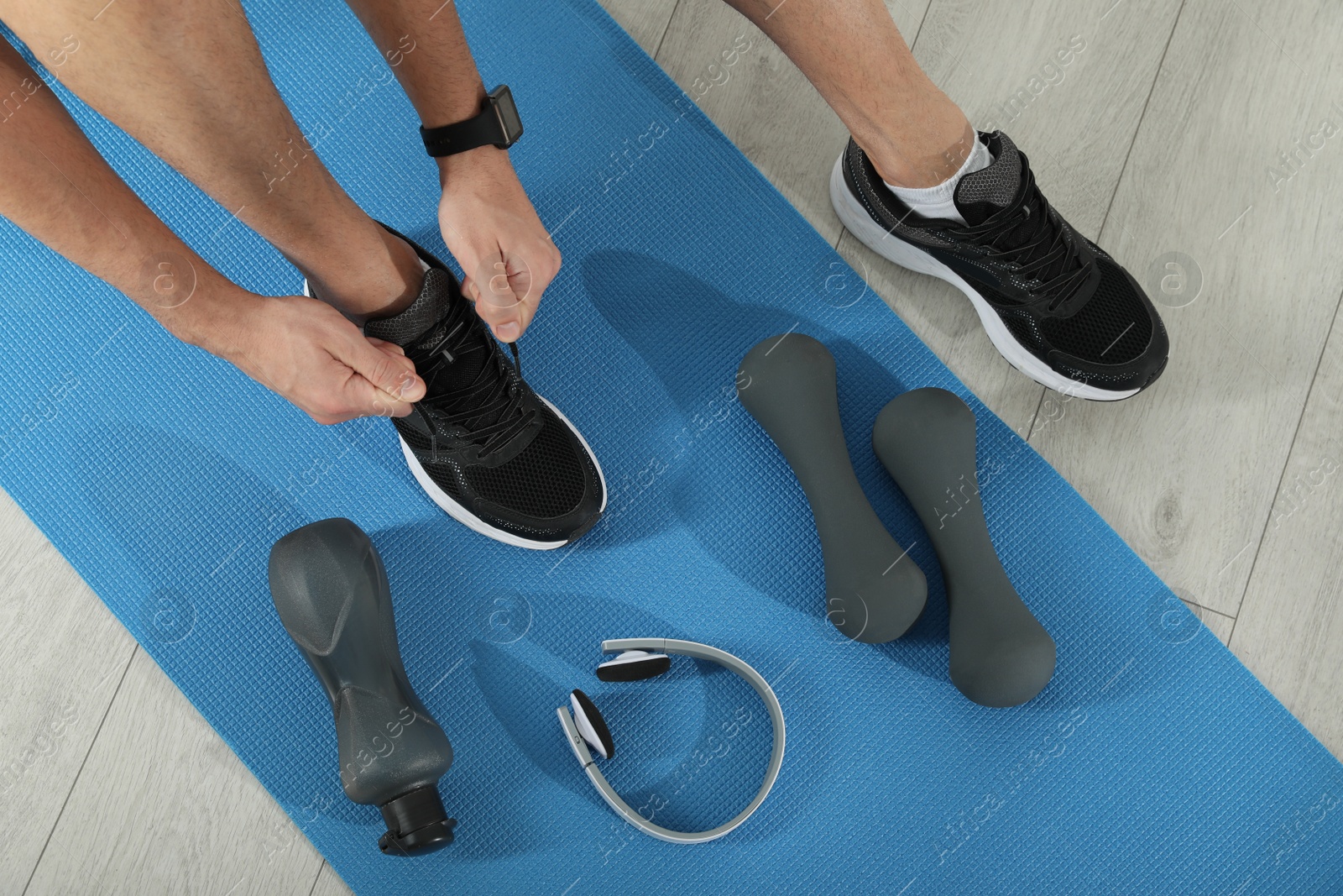 Photo of Top view of man tying shoelaces on yoga mat