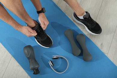 Top view of man tying shoelaces on yoga mat