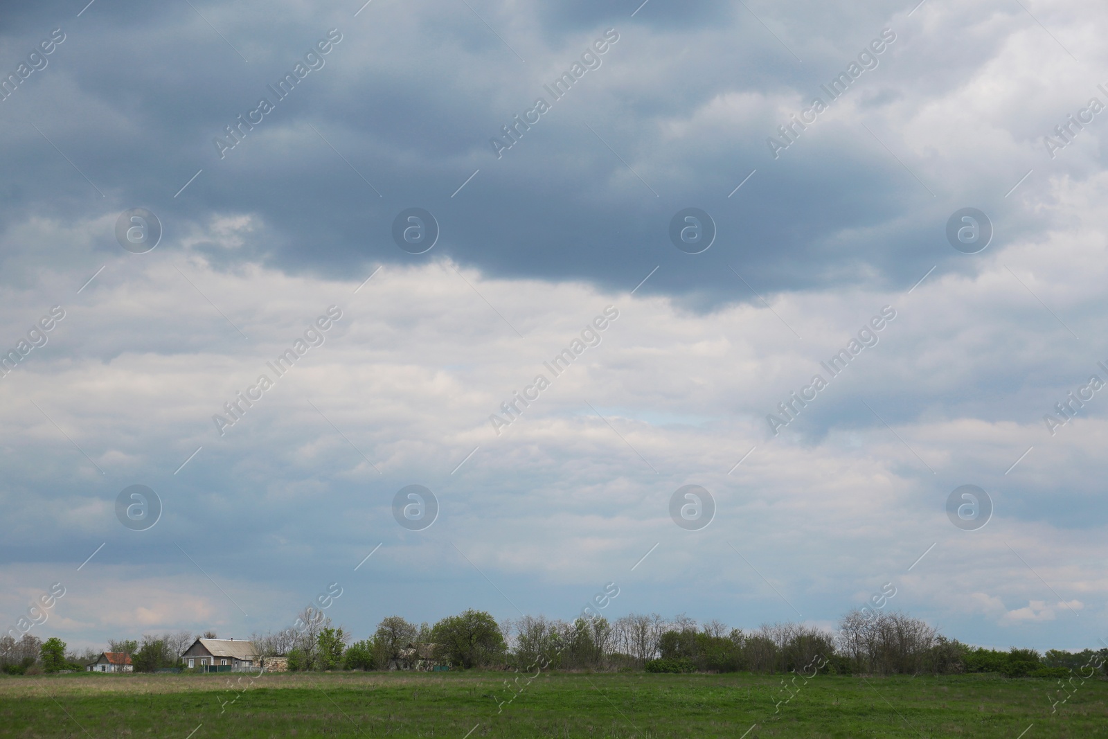 Photo of Houses under cloudy sky. Picturesque rural landscape