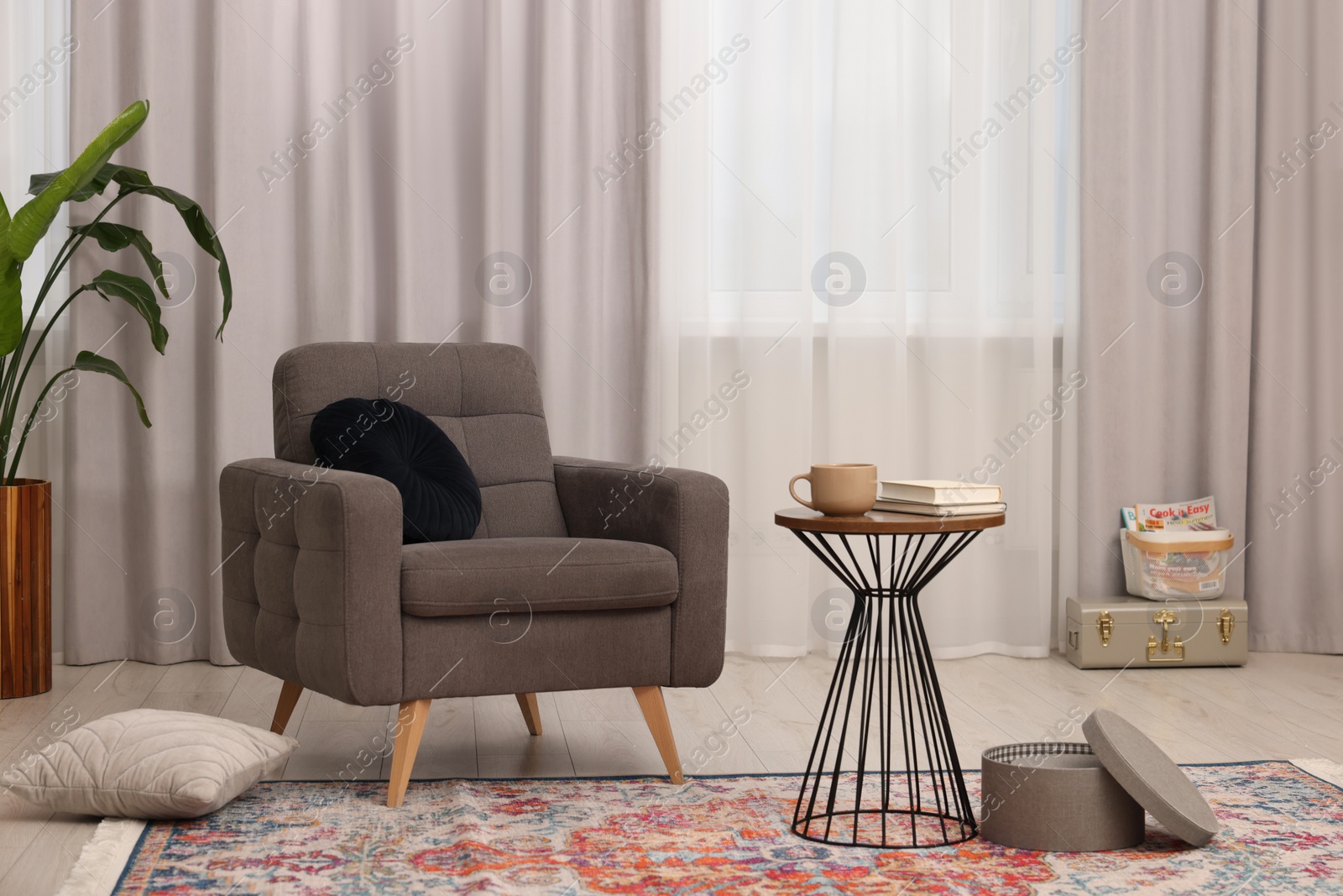 Photo of Stylish gray armchair and small table in living room. Interior design