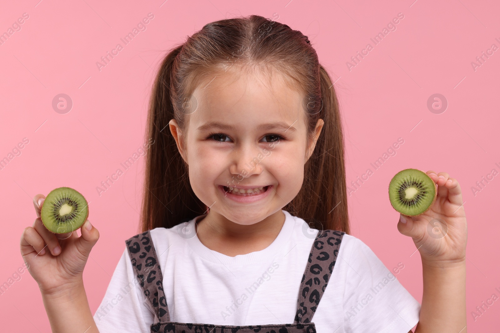 Photo of Happy girl with halves of fresh kiwi on pink background