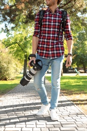 Photo of Young male photographer with professional camera in park