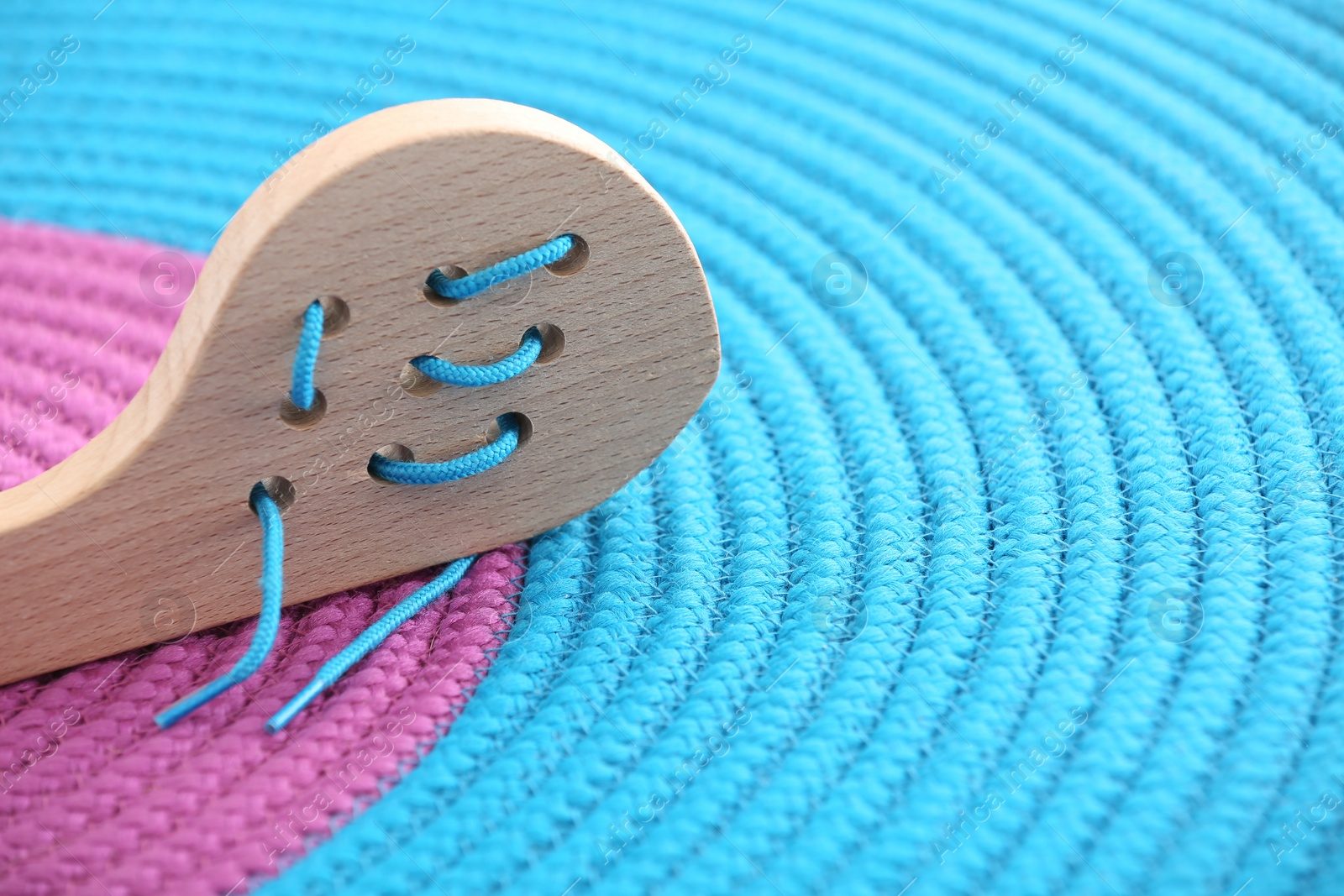 Photo of Motor skills development. Wooden lacing toy on color mat, closeup. Space for text