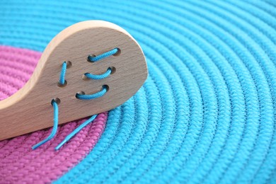 Photo of Motor skills development. Wooden lacing toy on color mat, closeup. Space for text