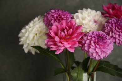 Photo of Bouquet of beautiful Dahlia flowers near dark grey wall, closeup