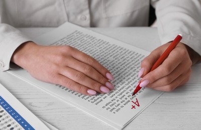 Photo of School grade. Teacher writing letter A with plus symbol on sheet of paper at white table, closeup