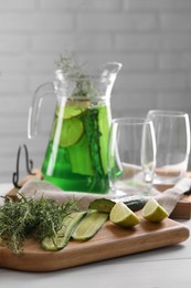 Photo of Fresh homemade refreshing tarragon drink and ingredients on white wooden table