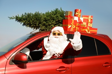 Authentic Santa Claus with presents and fir tree on roof driving modern car outdoors