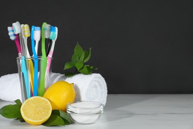 Toothbrushes, lemons and bowl of baking soda on white table against black background, space for text