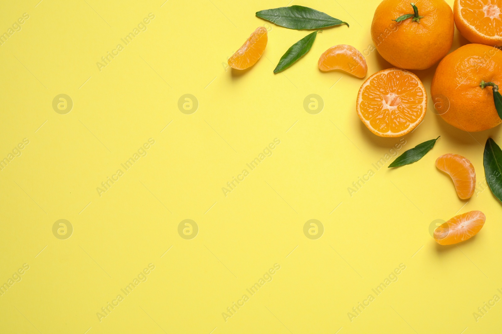 Photo of Flat lay composition with fresh ripe tangerines and leaves on light yellow background, space for text. Citrus fruit