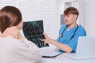 Doctor with neck MRI image consulting patient in clinic