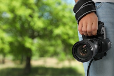 Image of Professional photographer with modern camera and blurred view of park, space for text