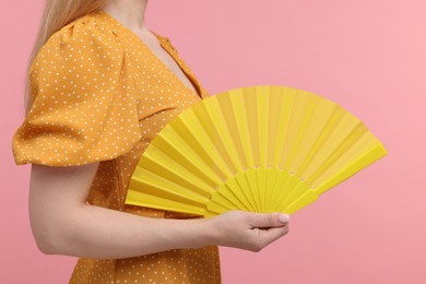 Photo of Woman with yellow hand fan on pink background, closeup