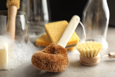 Photo of Cleaning brushes for dish washing on grey table, closeup