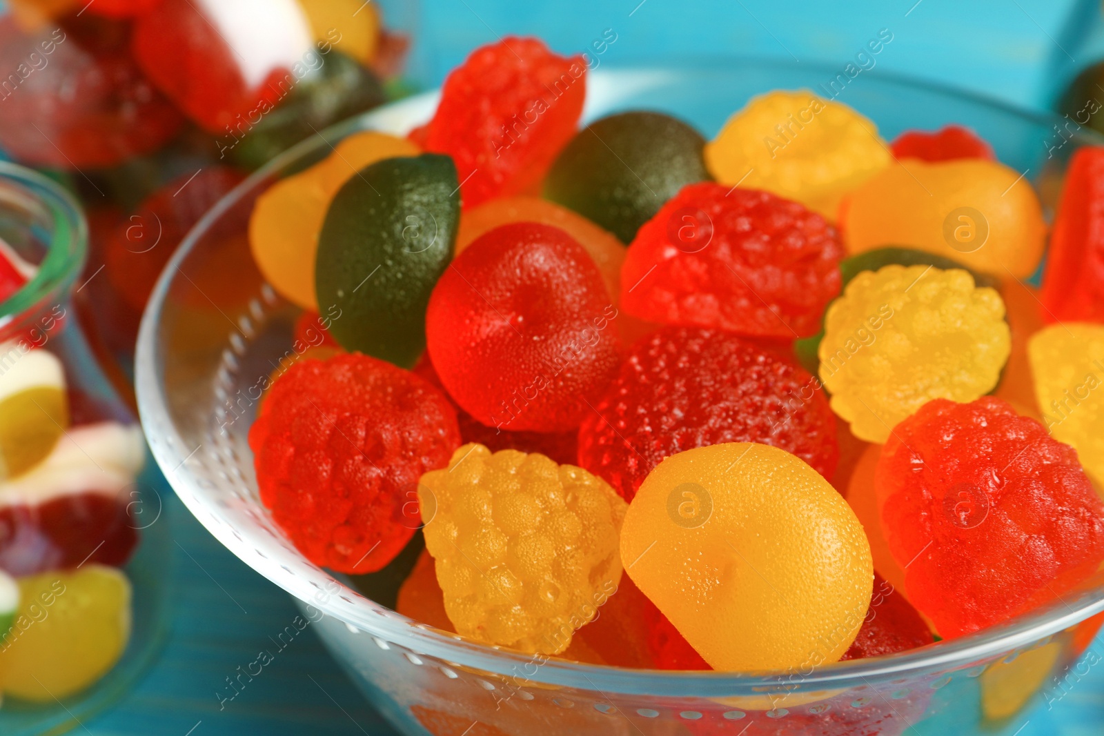 Photo of Delicious gummy fruit shaped candies in glass bowl, closeup