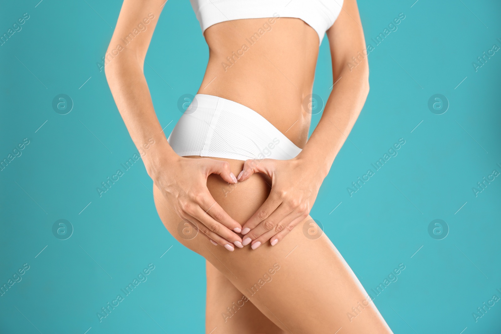 Photo of Closeup view of slim woman in underwear making heart with hands near thigh on color background. Cellulite problem concept