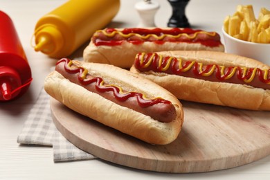 Photo of Fresh delicious hot dogs with sauces on white wooden table