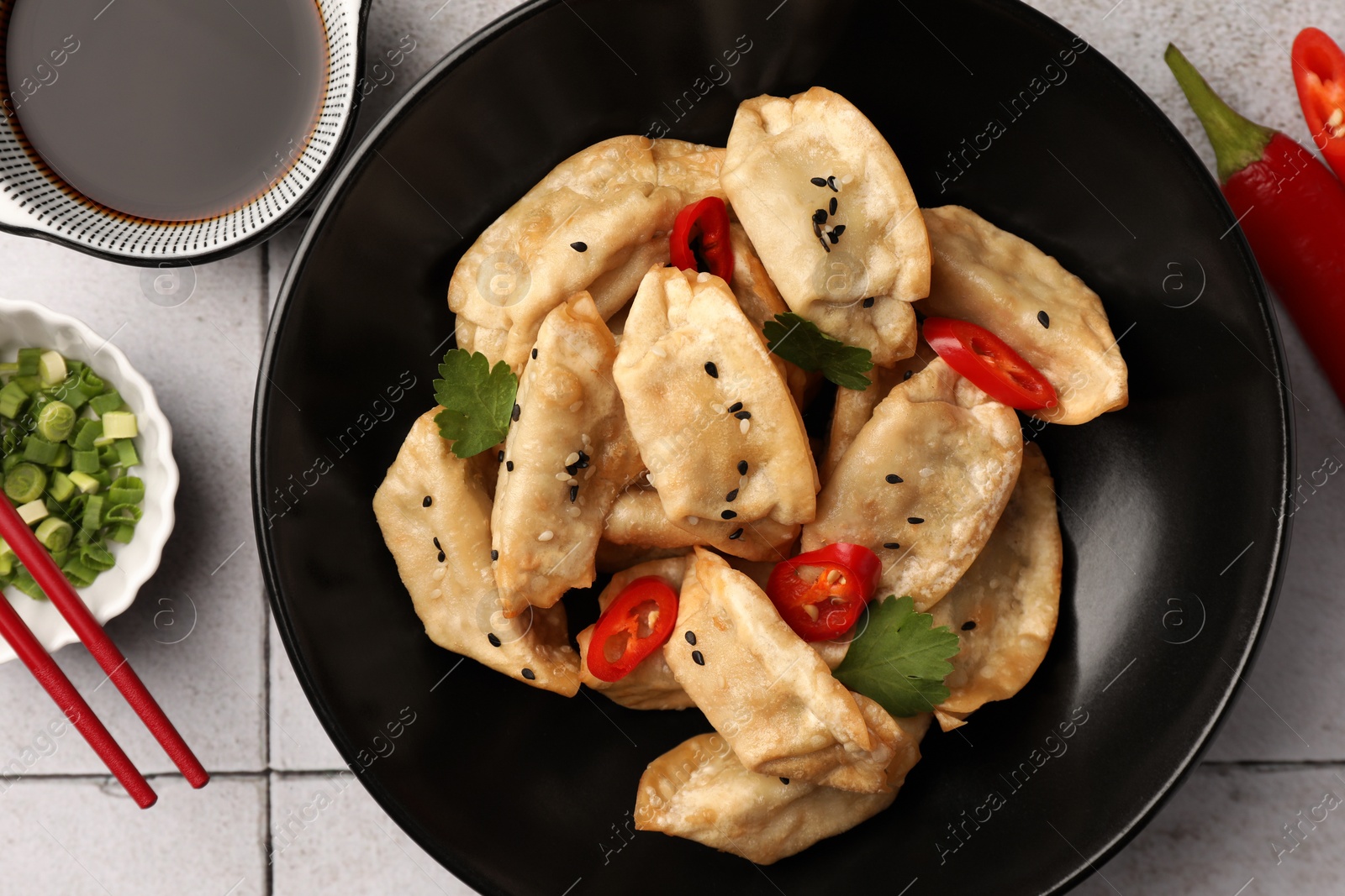 Photo of Delicious gyoza (asian dumplings) served on light tiled table, flat lay