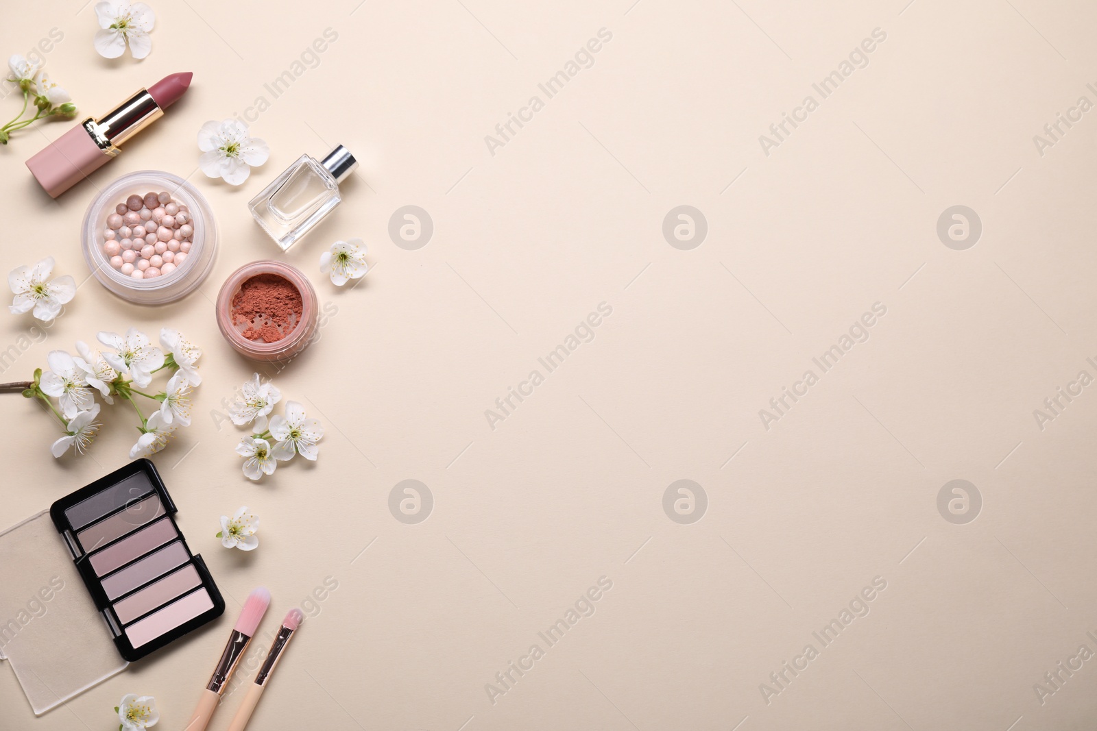 Photo of Flat lay composition with different makeup products and beautiful spring flowers on beige background, space for text