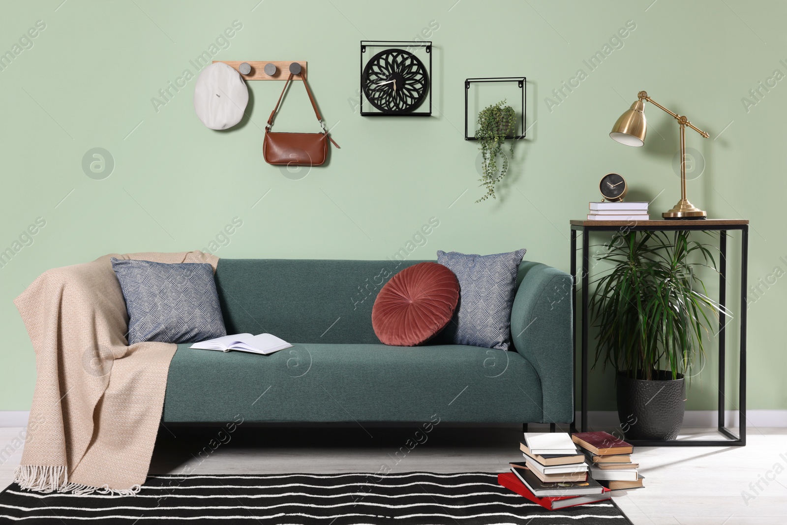 Photo of Stylish interior with comfortable sofa, blanket and cushions near console table