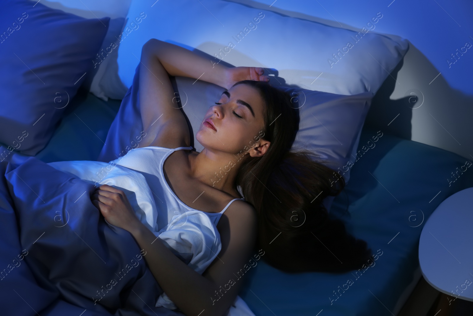 Photo of Young woman sleeping on soft pillow at night. Bedtime