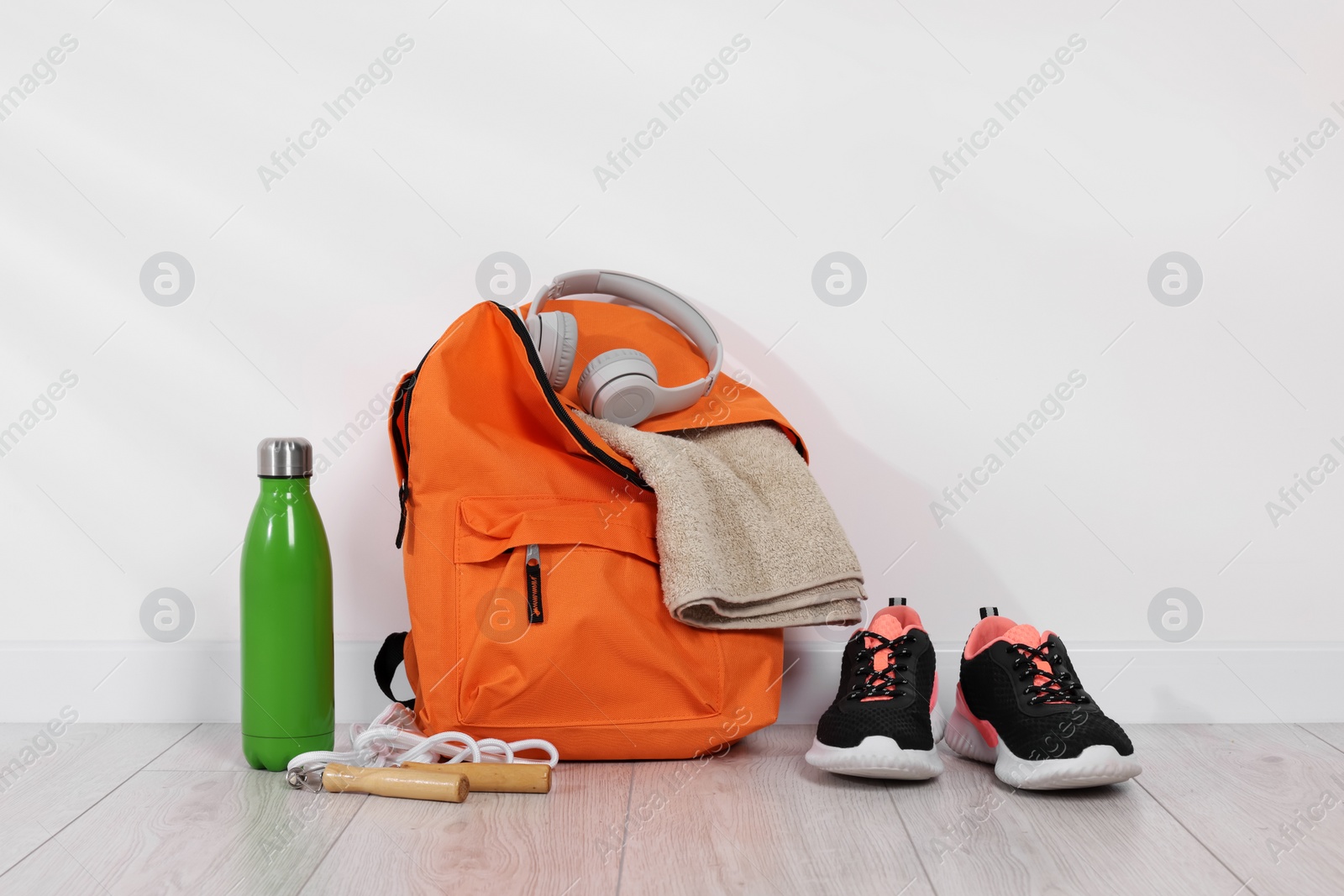 Photo of Backpack and sports equipment on floor near white wall